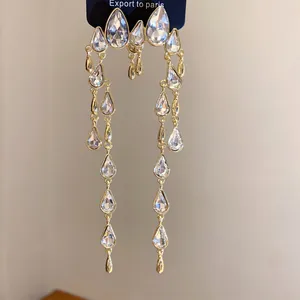 Detailed view of elegant teardrop tassel earrings with sparkling rhinestones in gold setting.