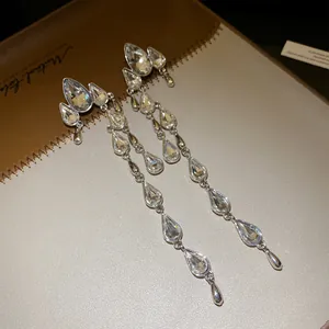 Close-up of silver-toned waterdrop tassel earrings with clear sparkling rhinestones