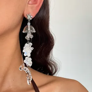 Detail close-up of translucent acrylic flower tassel earrings with glass droplets