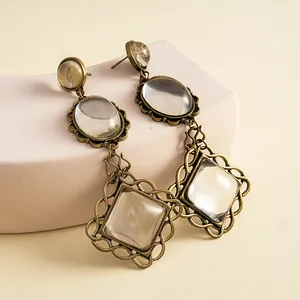 Close-up of vintage resin earrings with ornate lace-like antique gold metal borders.