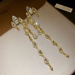 Detail of elegant long gold drop tassel earrings with sparkling clear waterdrop crystals