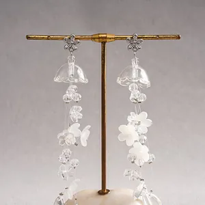 Close-up detail of elegant translucent acrylic flower tassel earrings on a gold stand