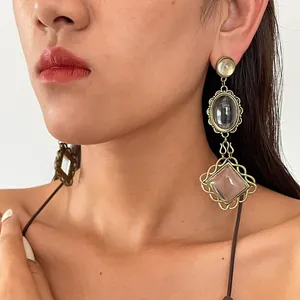 Close-up detail of vintage exaggerated metal earrings with resin pendants worn by a model