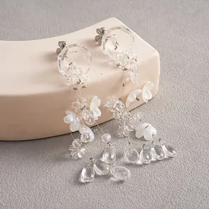 Close-up detail of translucent acrylic glass flower and teardrop fringe earrings.