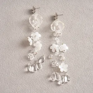 Close-up of translucent acrylic flower tassel earrings with clear waterdrop pendants.
