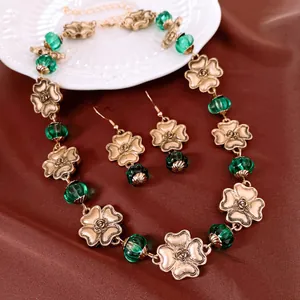 Detailansicht eines Vintage-Blumenschmucksets mit goldenen Metallblüten und grünen Glasperlen
