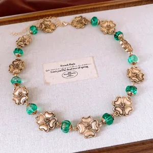 Halskette im Vintage-Stil mit goldenen Blumenanhängern und grünen Glasperlen Detail