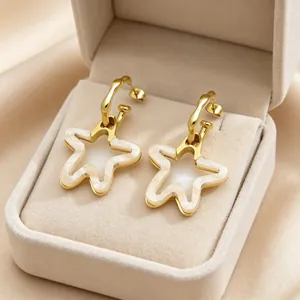 Gros plan détaillé de boucles d'oreilles étoile en acier doré et résine nacrée