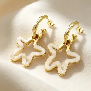 Gros plan de boucles d'oreilles élégantes en acier doré avec pendentifs étoiles en résine sur tissu