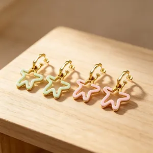 Gros plan sur des boucles d'oreilles étoiles dorées en acier et résine pastel
