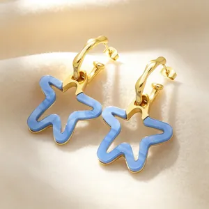 Gros plan de boucles d'oreilles créoles dorées avec pendentifs étoiles en résine bleue