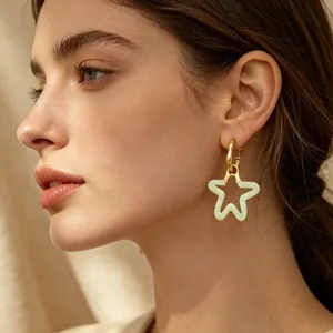 Gros plan sur des boucles d'oreilles créoles dorées avec pendentif étoile en résine