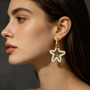 Gros plan d'un mannequin portant une boucle d'oreille en résine étoile évidée vert et or