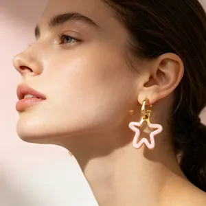 Gros plan d'un mannequin portant de douces boucles d'oreilles étoile rose et or