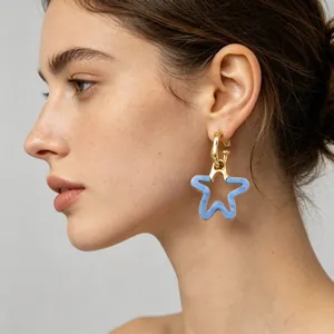 Gros plan d'un pendentif étoile en résine bleue sur une boucle d'oreille en acier doré