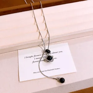 Detail view of the black stone bead and hexagram pendant on a silver snake chain