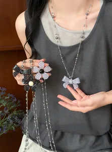 Detailopname van een lange vintage ketting met een gestippelde strik en bloembedels