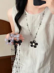 Detail van een vintage polkadot bloem- en strikketting met glazen kralen op model.