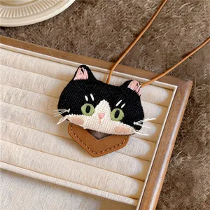 Close-up of a cute embroidered black and white cat pendant on a jewelry tray