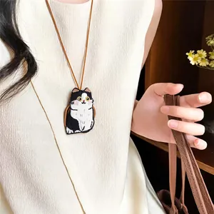 Close-up of cute embroidered cat pendant on minimalist brown leather cord necklace