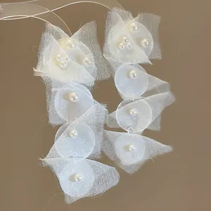 Nahaufnahme von eleganten weißen Chiffon- und Perlenohrringen für den Strandurlaub