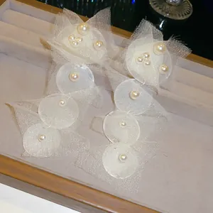 Detaillierte Nahaufnahme eleganter weißer Chiffon-Ohrringe mit dekorativen Perlen