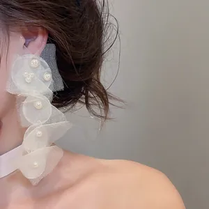 Detailaufnahme von eleganten langen Chiffon-Clip-Ohrringen mit Perlen für den Strandurlaub