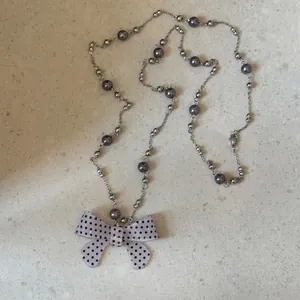 Detailopname van de lavendelkleurige acryl strik hanger met stippen en parelketting