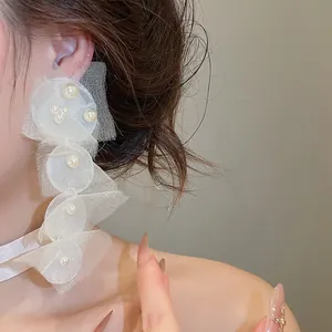 Detailansicht weißer Chiffon-Ohrringe mit eleganten Perlenakzenten an einem Model.