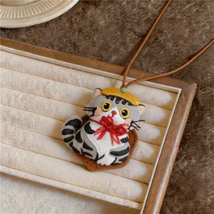 Detail shot of cute embroidered cat pendant necklace with yellow hat and red bow