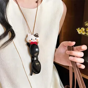Cute fabric cat pendant necklace used as a functional sunglasses holder on a cream top