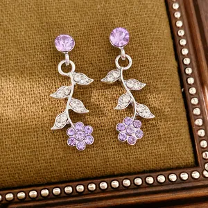 Macro di eleganti orecchini pendenti con fiori di cristallo viola e foglie d'argento