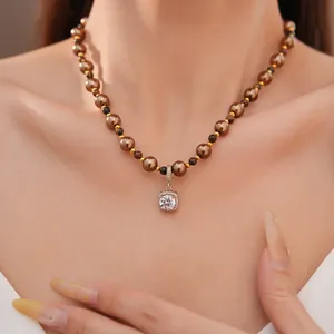 Detailopname van een tijgeroog- en parelketting met vierkante zirkoonhanger op een model