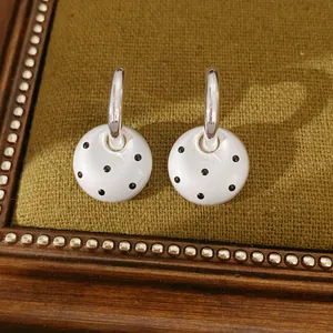 Detailansicht von eleganten silbernen C-Ohrringen mit weißen Emaille-Punkten Anhänger.