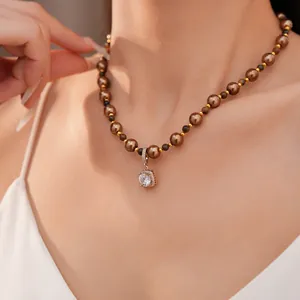 Detailweergave van de bruine parelketting met tijgeroog en zirkoon hanger.
