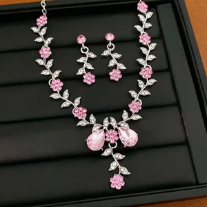 Nahaufnahme von Halskette und Ohrringen mit eleganten rosa Kristallblumen und Blattdesign
