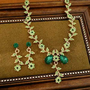 Dettaglio di una parure vintage con cristalli verde smeraldo, motivi a fiori e foglie.