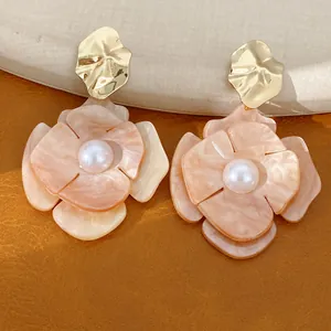 Close-up of peach acrylic flower earrings with gold crumpled metal and white pearls