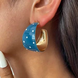 Nahaufnahme des blauen Retro-Punkt-Ohrrings in C-Form mit elegantem goldenem Innenfinish