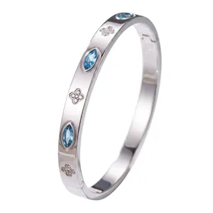 Silbernes Edelstahlarmband mit blauen Edelsteinen und funkelnden Kleeblatt-Motiven.