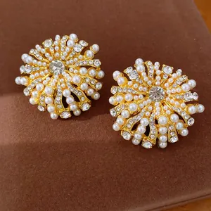 Nahaufnahme von eleganten goldfarbenen Blumenohrsteckern mit Perlen und Strasssteinen