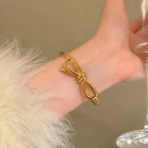 Gros plan d'un élégant bracelet jonc ouvert à nœud papillon plaqué or 18 carats