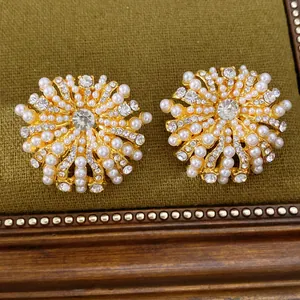 Nahaufnahme von goldfarbenen Blumenohrsteckern mit Perlen und Strass auf Samttablett
