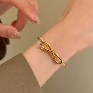 Gros plan d'un bracelet manchette noeud plaqué or 18K au poignet montrant sa texture fine.