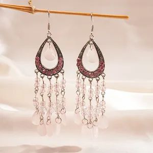 Gros plan détaillé de boucles d'oreilles pendantes en résine rose de style chinois avec pompons
