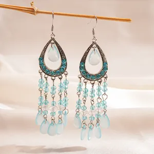 Vue détaillée de boucles d'oreilles à pompons turquoise avec perles de résine sur branche
