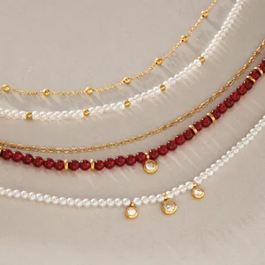 Detailopname van een elegante gelaagde kettingset met rode agaat en parels in goud