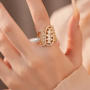 Close-up of a gold geometric twisted oval ring with intricate cubic zirconia stones.
