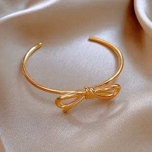 Détail exquis en gros plan d'un bracelet jonc ouvert plaqué or 18 carats avec un nœud