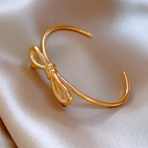Détail d'un bracelet jonc ouvert plaqué or 18 carats avec un motif de nœud épuré.